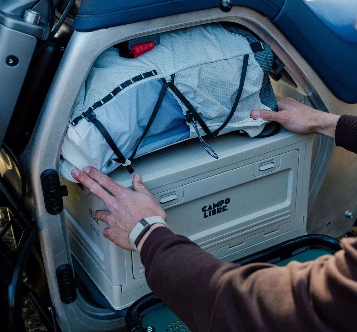 La partie coffre de la moto Any LUV1, avec une caisse en plastique et un sac à dos