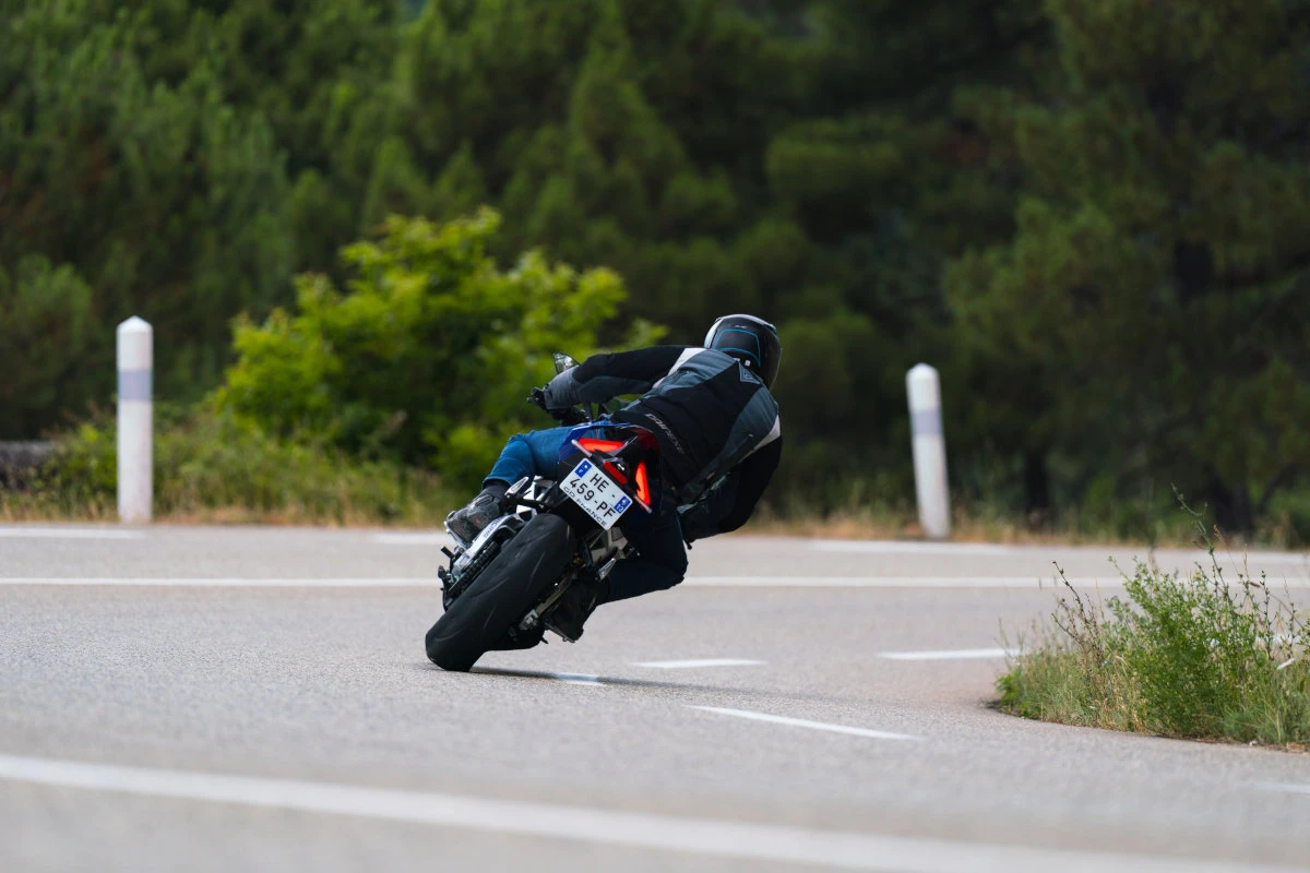 The rear of the bike in a curve on the road with its bright red lights