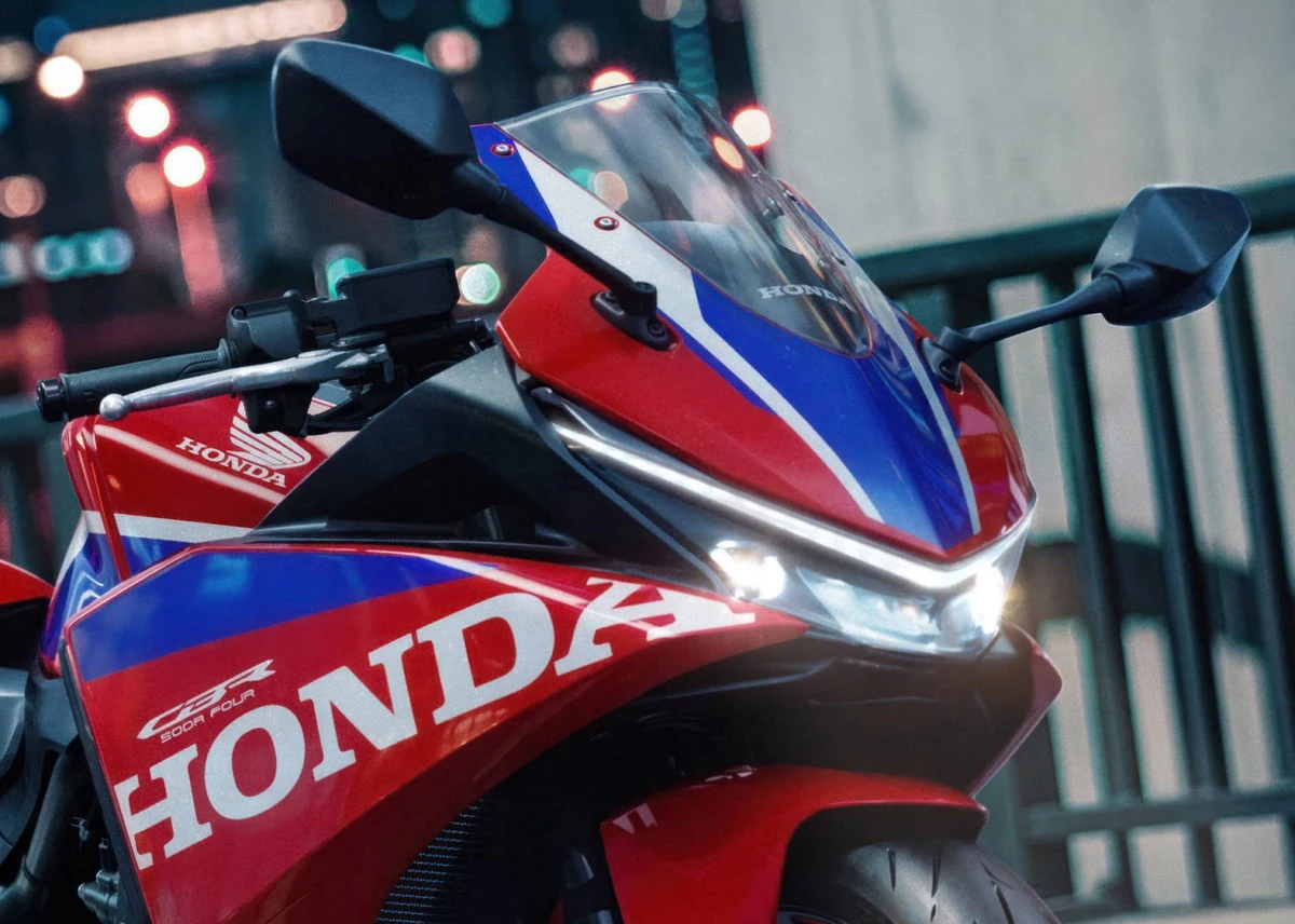 La partie avant d'une Honda CBR 500 R Four rouge avec les phares allumés.