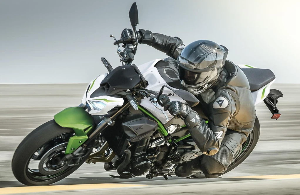Une moto Kawasaki Z 900 blanche et verte roulant à l'attaque avec un motard habillé en noir