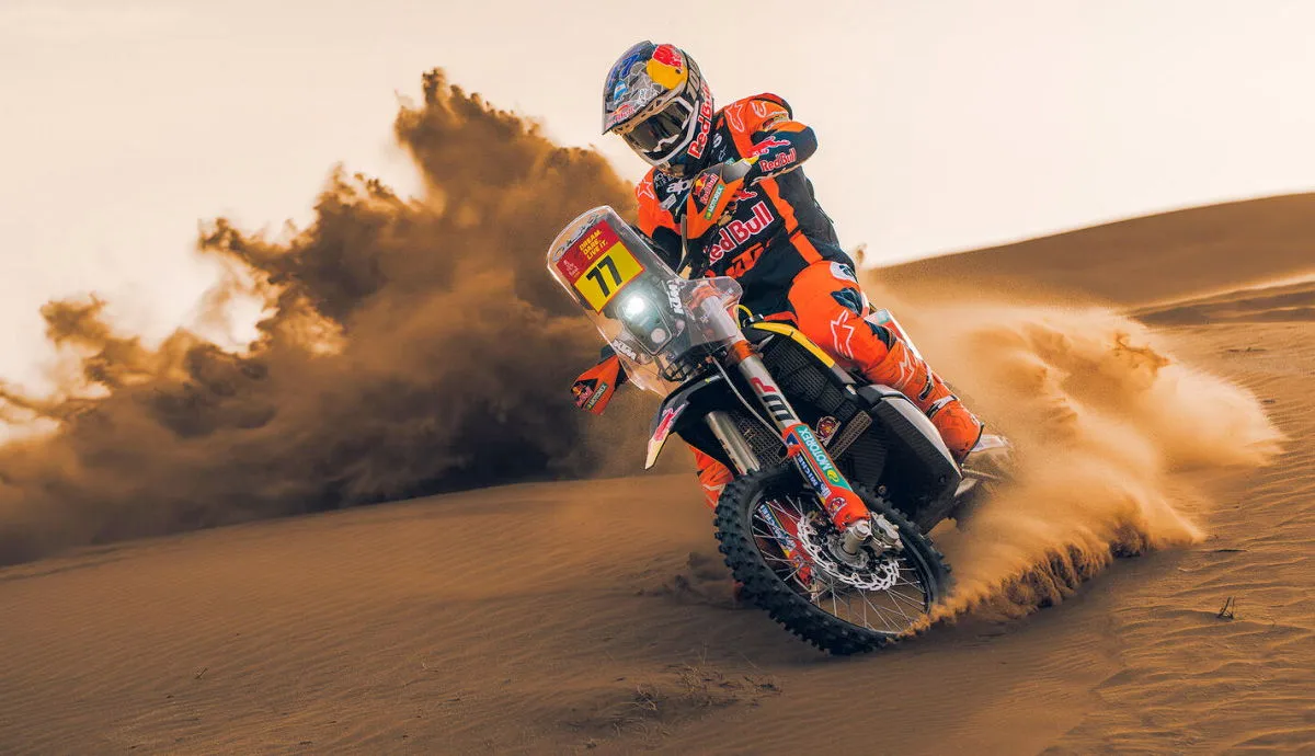 Une KTM 450 Rally de 2027 dans le désert avec du sable soulevé par la moto