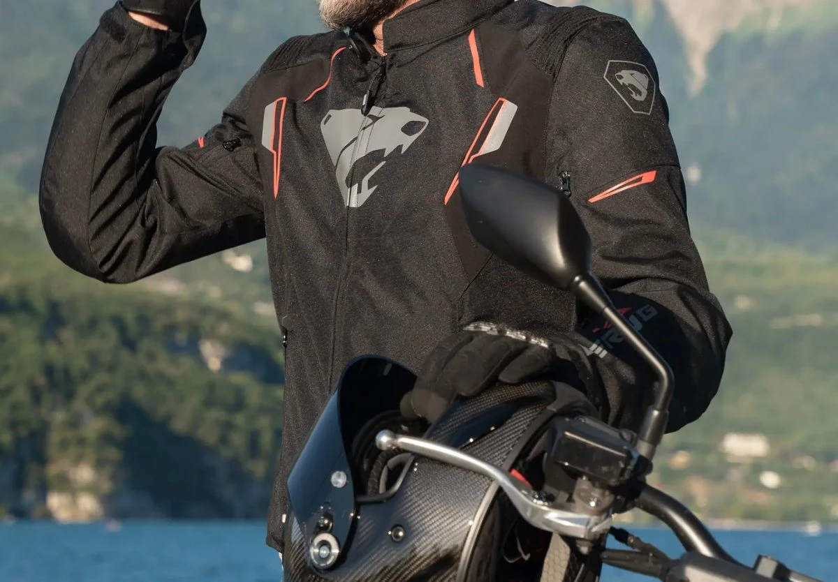 Un blouson Bering Thunder, un casque de moto en carbone et une vue sur un lac.