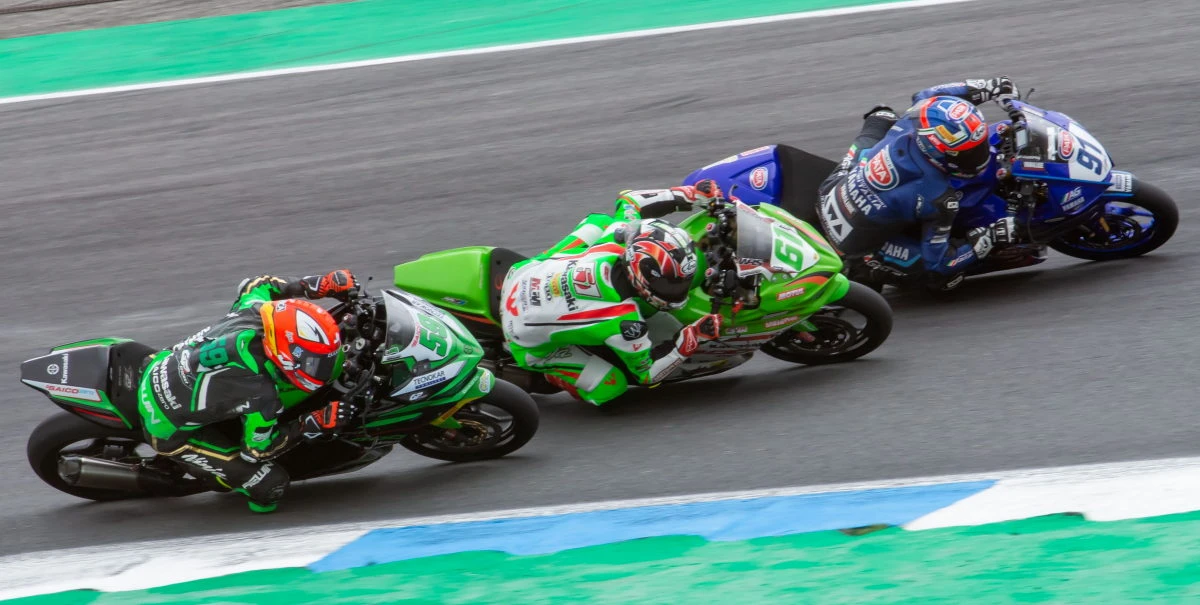 Deux motos vertes et une moto bleu sur circuit
