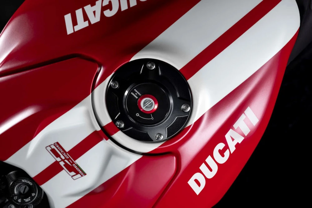 Gros plan sur le logo blanc Ducati apposé sur le réservoir rouge d'une moto sportive haut de gamme.