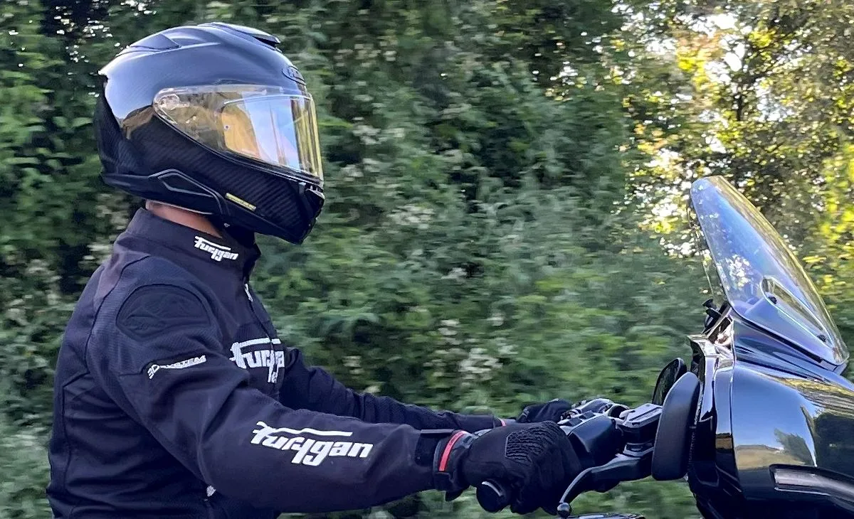 Un casque HJC Rpha 72, un blouson moto Furygan, des feuilles d'arbres et l'avant d'une Harley-Davidson Street Glide Limited