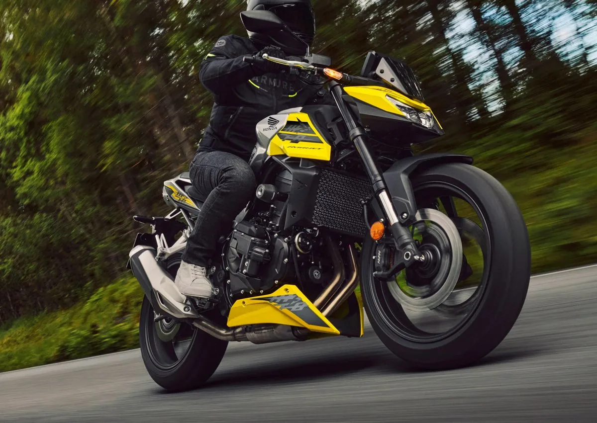 Une Honda CB750 Hornet jaune sur une route et des arbres avec un effet de flou