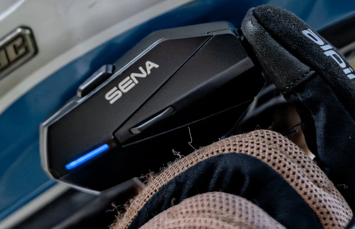 Un intercom Sena Apex, un gant de moto et un casque de moto blanc avec une bande bleu basse