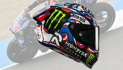 Un casque HJC Rpha 1 v2 en carbone avec le coloris Snow Diablo et une moto Yamaha M1 derrière