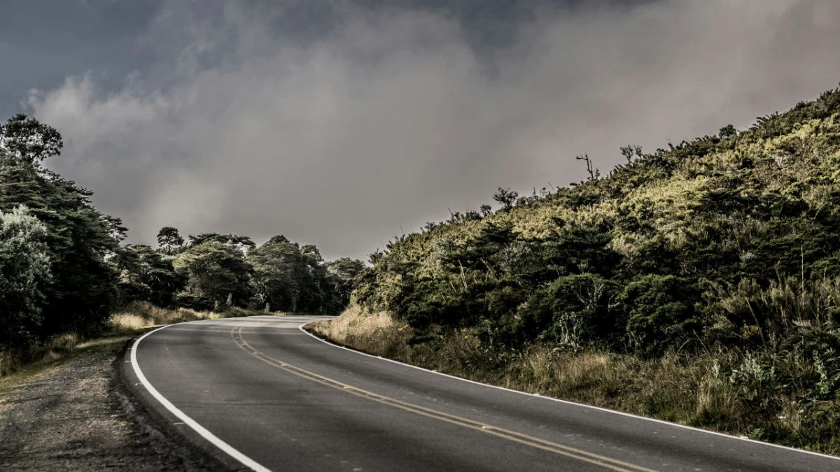 Un virage sur une route Costa Ricaine entouré de végétation sous un ciel nuageux