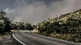 Un virage sur une route Costa Ricaine entouré de végétation sous un ciel nuageux