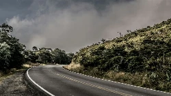 Un virage sur une route Costa Ricaine entouré de végétation sous un ciel nuageux