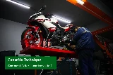 Mécanicien inspectant la chaîne d'une moto Yamaha 125 sur un pont d'atelier pour le contrôle technique moto.