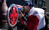 Marco Bezzecchi embrasse son casque, arborant fièrement le drapeau Italien sur le dos.