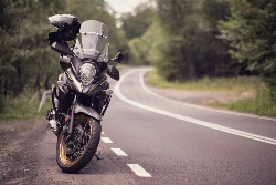Une Suzuki VStrom avec un casque sur le rétroviseur sur le bord d'une route