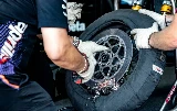 Un technicien manipulant une roue de moto avec un disque de frein en carbone et une couverture chauffante.
