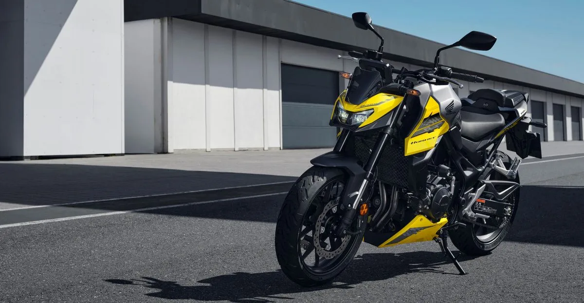 Une Honda CB750 Hornet jaune devant des garages