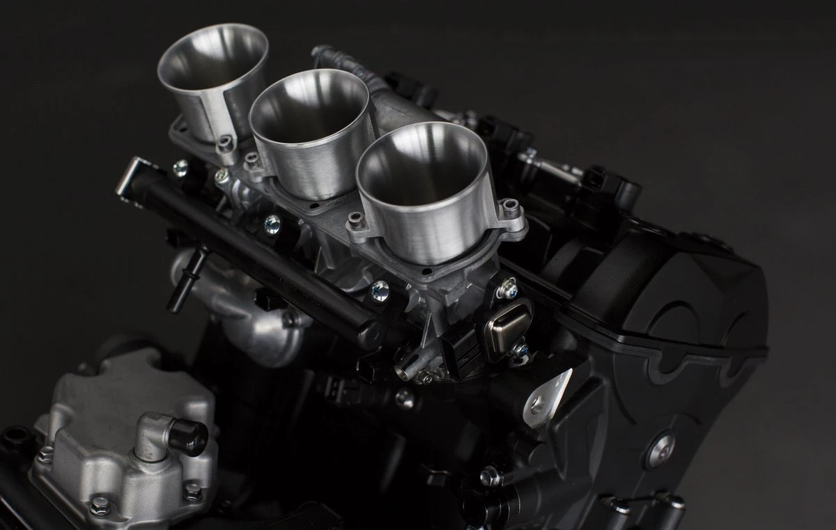 3 tubos de admisión y la parte superior del motor de un Triumph de 3 cilindros