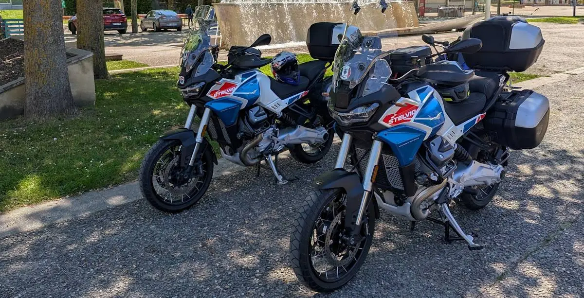 Deux motos Moto-Guzzi 1000 Stelvio Duecento Tributo avec de la bagagerie, de la pelouse, des arbres et des voitures