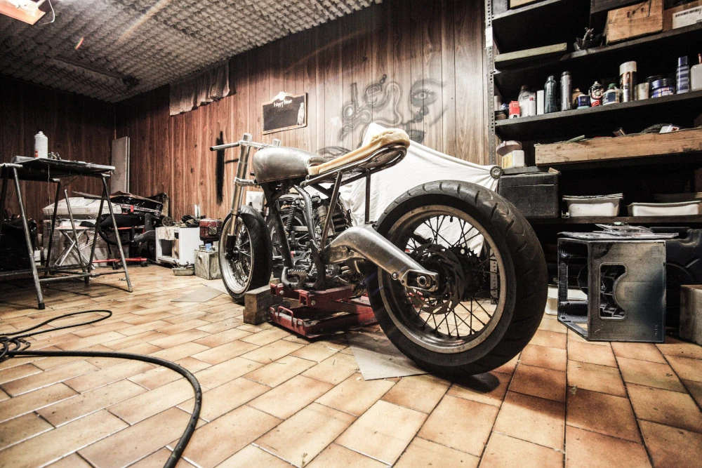 Un garage moto avec un concept et plein d'outil, avec un revêtement sol en carrelage
