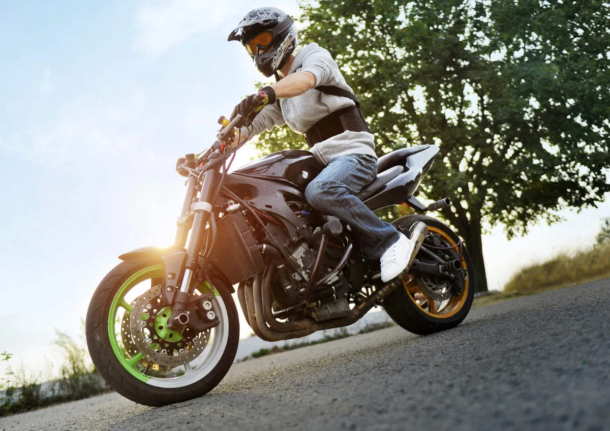 Moto d'un stunter avec son pilote équipé d'un casque cross et d'une dorsale