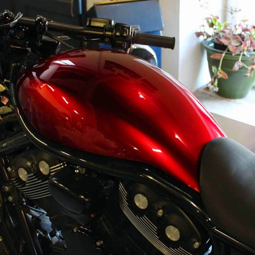 Application d'une peinture Candy rouge sur un réservoir de moto