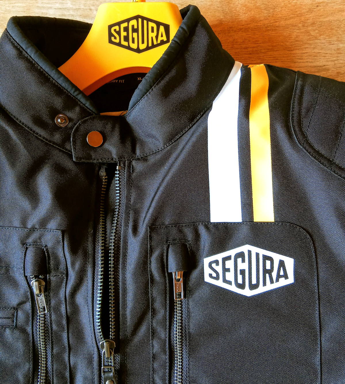 Le haut d'Un blouson moto textile noir Segura Scorpio avec un cintre jaune