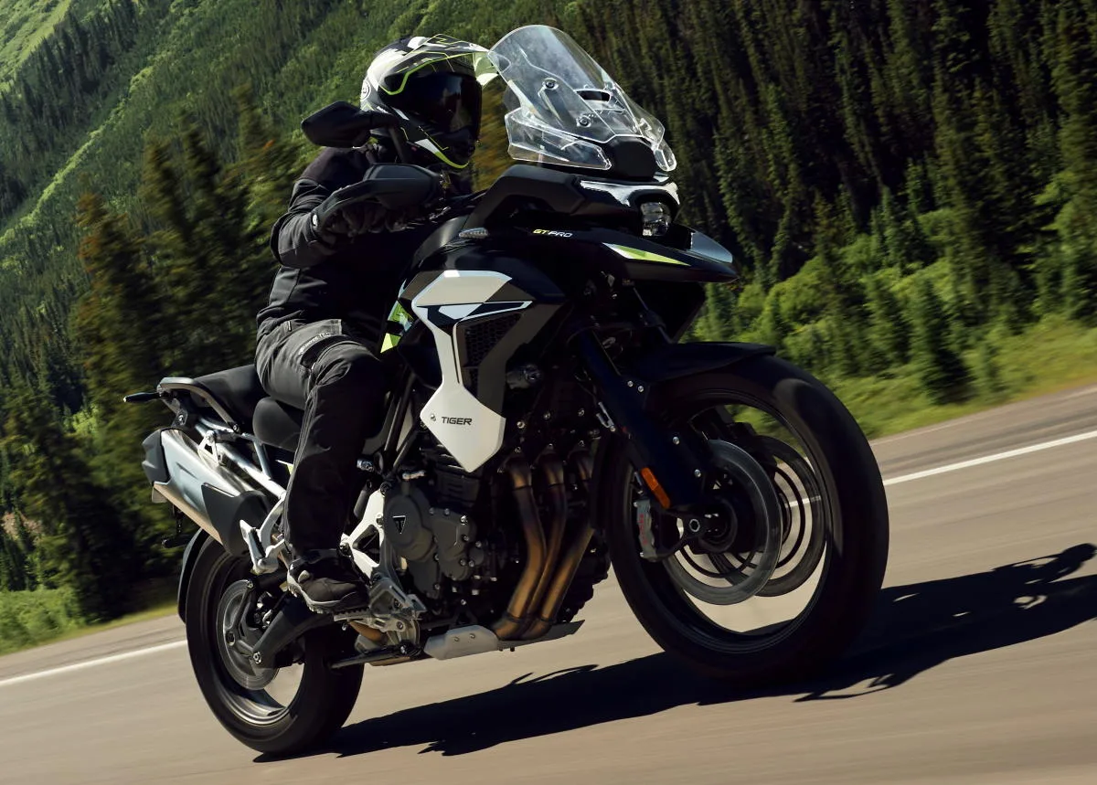 Une moto Triumph Tiger 1200 GT de 2027 sur une route et une foret de montagne