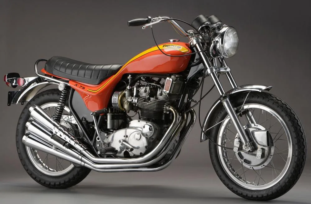 An orange Triumph 750 X-75 Hurricane motorcycle on a gray background