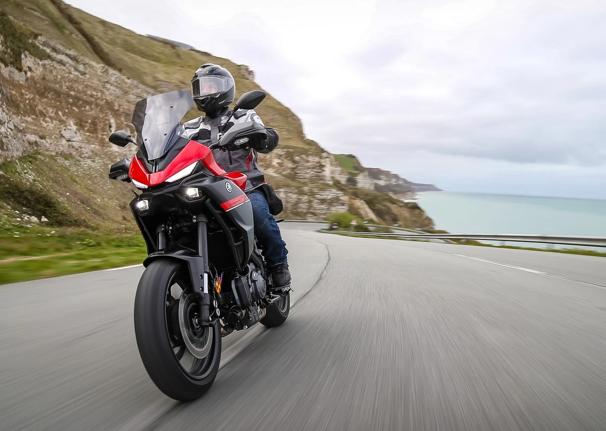 Une Yamaha Tracer 7 rouge sur la route et la mer derrière