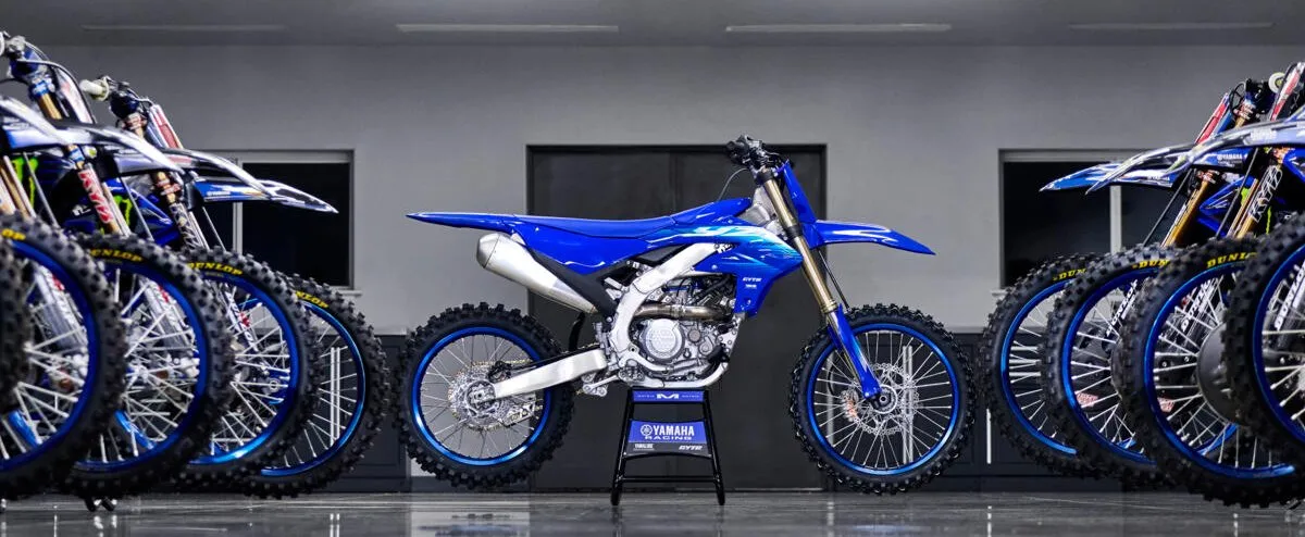 une Yamaha YZ 250 F dans un garage et des roues avant de motos de compétition