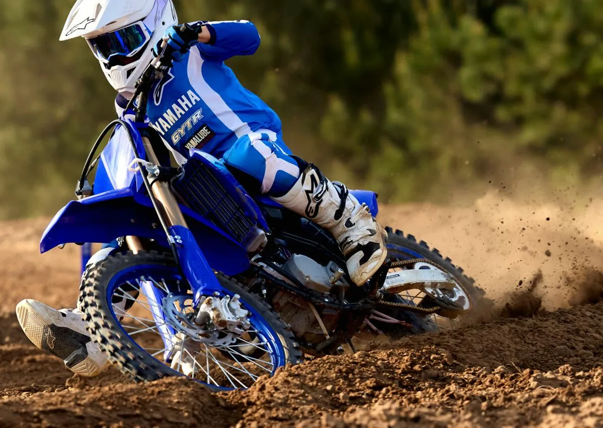 Une Yamaha YZ 85 bleu, un terrain de cross, un pilote avec un casque blanc