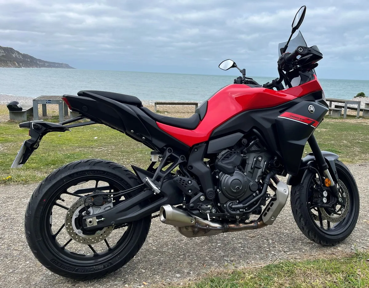 Une Yamaha Tracer 7 rouge, une plage de galets et la mer
